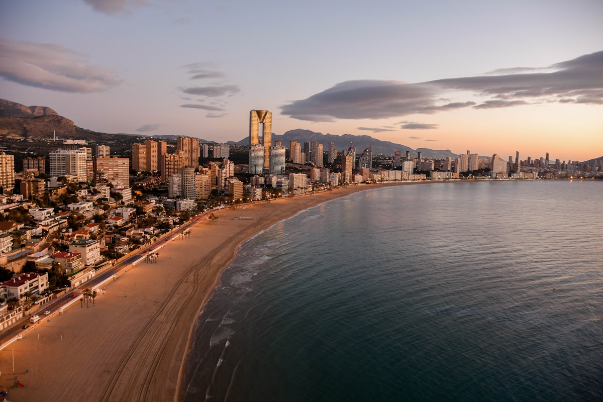 El perfil de rascacielos de Benidorm curvándose alrededor de la playa de Poniente al amanecer